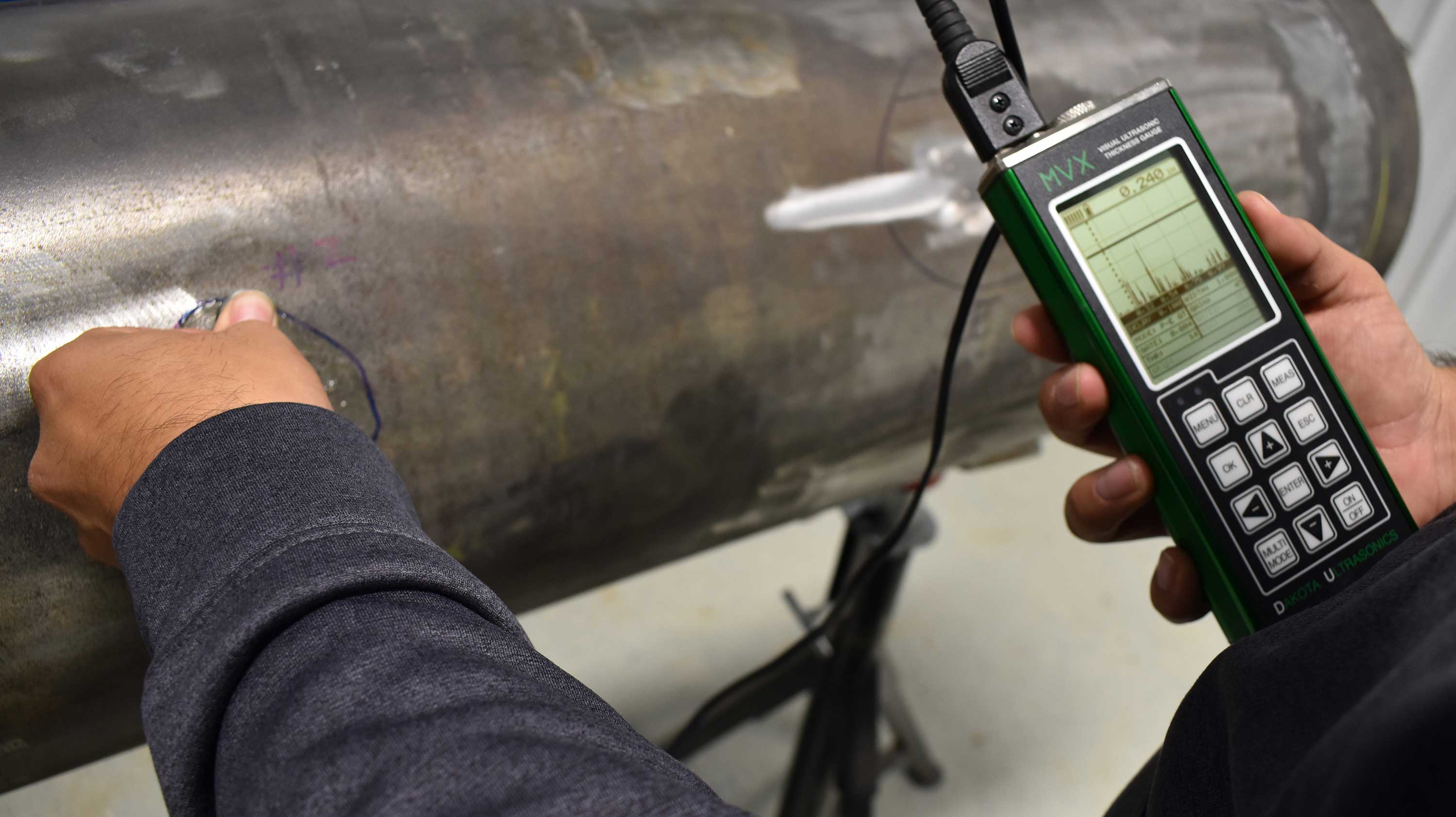 Technician using MVX ultrasonic thickness gauge to measure pipe wall thickness