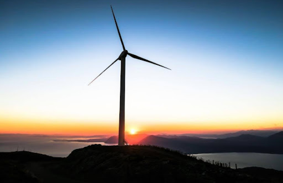 A wind turbine against the setting sun